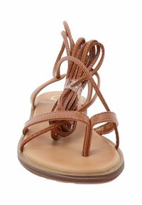 Sandal nera con cinturini e suola piatta, dotata di una morbida soletta color pesca e una suola in gomma marrone flessibile.