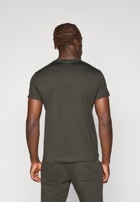 Donkergroen t-shirt met korte mouwen van katoen, met een ronde hals en een gladde textuur, weergegeven vanuit de achterkant.