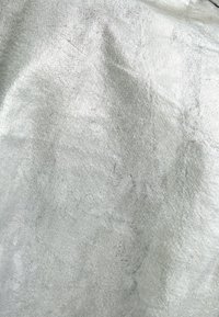 Tessuto argenteo con una finitura metallica e una consistenza morbida, caratterizzato da pieghe sottili e un motivo di superficie uniforme.