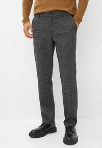 Pantaloni a quadri grigi realizzati in tessuto testurizzato, con una vestibilità slim, passanti per cintura e chiusura a un bottone. Abbinati a scarpe nere.