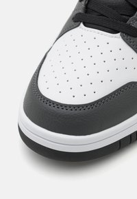 Gray and white leather sneaker with perforated toe box, textured upper, flat black laces, and a rubber sole with white midsole detailing.