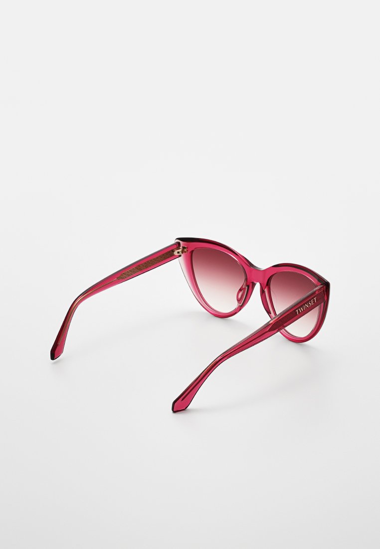 Kittenaugen-Sonnenbrille mit einem durchsichtigen magentafarbenen Rahmen und verlaufenden Gläsern. Verfügt über ein schlankes Design und goldene Hardware-Akzente an den Bügeln.