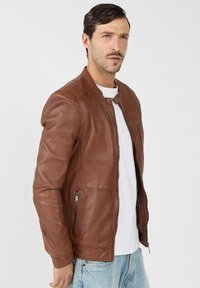 Braune Lederjacke mit Reißverschluss, Knopfkragen, seitlichen und Brusttaschen. Glatte Textur, taillierte Passform und lässiger Stil.