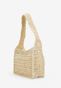 Borsa in paglia intrecciata di un leggero beige, con una larga tracolla, forma rettangolare e una texture aperta con sottili motivi a scanalature.