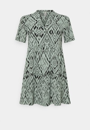 Robe à manches courtes et col en V avec jupe à étages, présentant un motif géométrique abstrait noir sur un tissu vert clair.