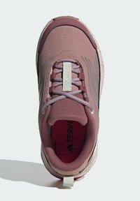 Hellrosa Sport-Schuh mit strukturiertem Obermaterial, Schnürverschluss, gepolstertem Kragen und einer weiß gesprenkelten Sohle mit einer Lasche an der Ferse.