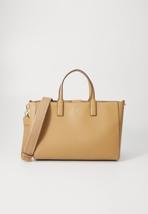 Brązowa torba na ramię z podwójnymi górnymi uchwytami i odpinanym szerokim paskiem z wytłoczonym logo marki na białym tle.