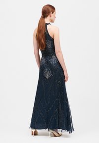 Abito da sera blu navy con corpetto attillato, collo all'americana e gonna fluida. Include un intricata lavorazione di perline in un motivo geometrico.