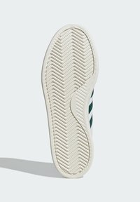 Bielo-čierne tenisky s bielou podrážkou a zelenými akcentmi. Majú vzor rybej kosti a zaoblené okraje pre lepšiu trakciu. Hladký gumový povrch.