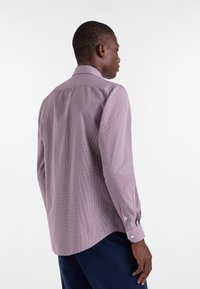 Camicia a maniche lunghe di colore viola chiaro con motivo a quadretti, polsini con bottone e colletto classico. Realizzata in un tessuto morbido e testurizzato.