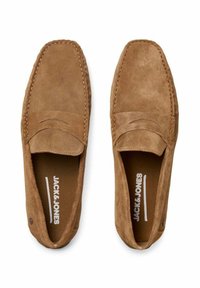 Mocassini in suede marrone con un design cucito e una cucitura frontale rialzata. L'interno presenta un logo e un rivestimento in tessuto morbido.