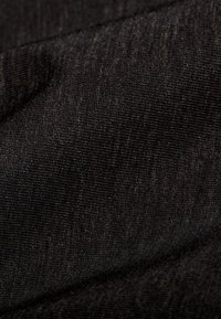 Gros plan d'un tissu tissé foncé montrant une texture côtelée fine et des plis subtils créant des ombres et des reflets.