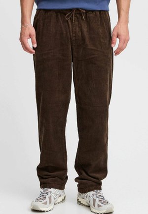 Brune kordfløjspants med en afslappet pasform, der har en elastisk talje og snøre. Stoffet har en vertikal ribbet tekstur.