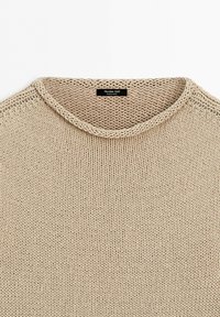 Beige knitted sweater with round neck and visible label inside collar reading "Massimo Dutti Made in Spain".