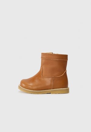 Bottine enfant en cuir marron avec semelle en caoutchouc beige, bout arrondi et coutures visibles sur fond gris clair.
