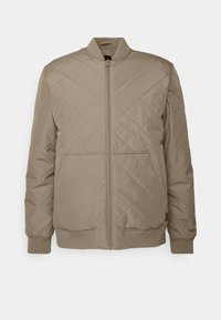 Quiltet beige bomberjakke med glidelås foran, to nedre lommer, ribbede mansjetter og stå-opp krage. Glatt polyester materiale.