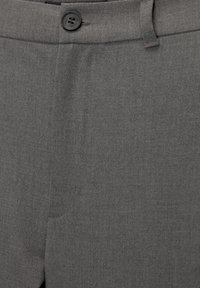Close-up van een grijze pantalon met een tailleband, een zwarte knoop en een textuurdetail op de stof.