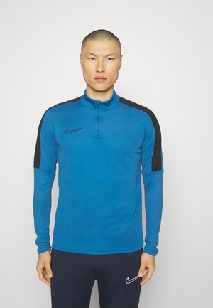 T-shirt à manches longues Nike en bleu, avec un col zippé, des accents noirs aux épaules et une coupe ajustée, fabriqué à partir d'un matériau léger.