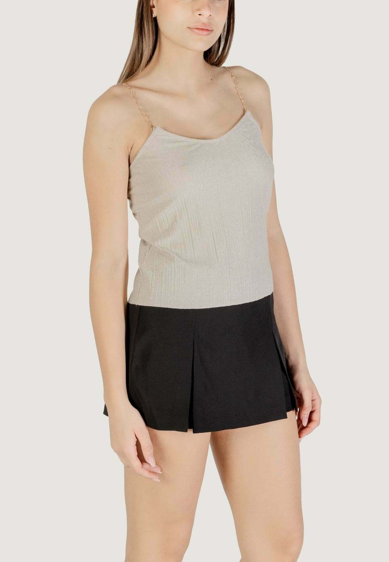 Top senza maniche grigio chiaro con una texture a coste e sottili spalline a catena, abbinato a una gonna nera plissettata.