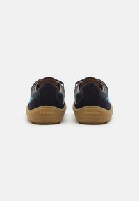 Scarpe in suede e pelle blu navy con suola in gomma color nocciola, caratterizzate da dettagli di cucitura e un logo sul tallone. Design a profilo basso.