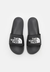 Sorte sandaler med teksturert stropp og hvit logo, med flat såle og åpen tå-design for ventilasjon og komfort.
