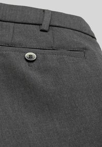 Graue Stoffhosen haben eine glatte Textur, eine Gesäßtasche mit einem silbernen Knopfverschluss und gestickte Details am Taillenbund.
