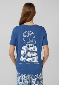 T-shirt en coton bleu à manches courtes, avec une illustration graphique blanche d'une femme au dos et le texte "PROFITEZ DE CHAQUE INSTANT".