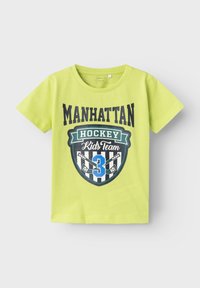 Limegrünes T-Shirt mit kurzen Ärmeln, das ein Wappen-Design mit "Manhattan Hockey Kids Team" und der Nummer 3 in blauen und schwarzen Streifen zeigt.