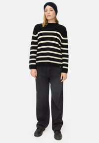 Zwart-wit gestreepte gebreide trui met een ronde hals, gecombineerd met zwarte wijde jeans en zwarte schoenen. Getextureerde stof en een relaxed fit.