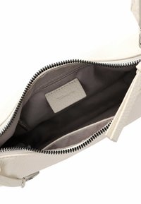 Off-white leather handbag interior, featuring a smooth gray fabric lining, zippered closure with black hardware, and a small brand label.