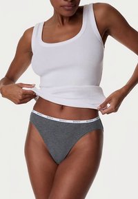 Grijze string met een witte elastische tailleband bedrukt met "BODY". Draagt een wit geribd tanktopje. Glad katoenen stof.