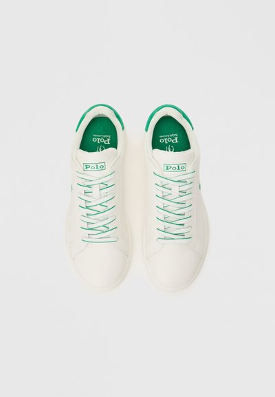 Λευκά αθλητικά παπούτσια με πράσινες λεπτομέρειες, που διαθέτουν λείο υλικό επάνω, πράσινα κορδόνια και λογότυπο στη γλώσσα. Στρογγυλή μύτη και επίπεδη σόλα.