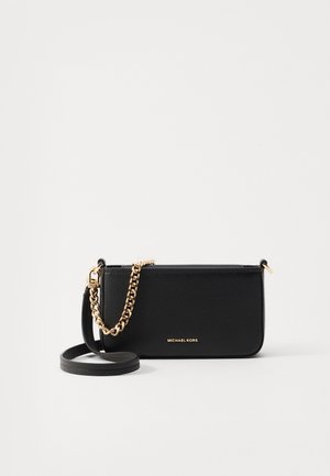 Sac bandoulière en cuir grainé noir avec détail chaîne dorée et logo Michael Kors sur le devant, sur fond blanc.