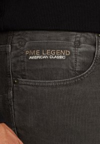 Tessuto di corduroy grigio con una texture rigata, che presenta un'etichetta con il logo "PME Legend American Classic" in ricamo beige e bianco.