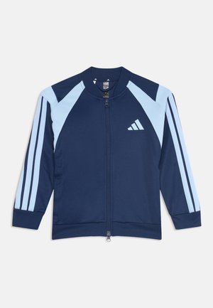 Marineblå og lyseblå Adidas lynlåstrøje med tre striber på ærmerne og logo på brystet, lagt fladt på en hvid baggrund.
