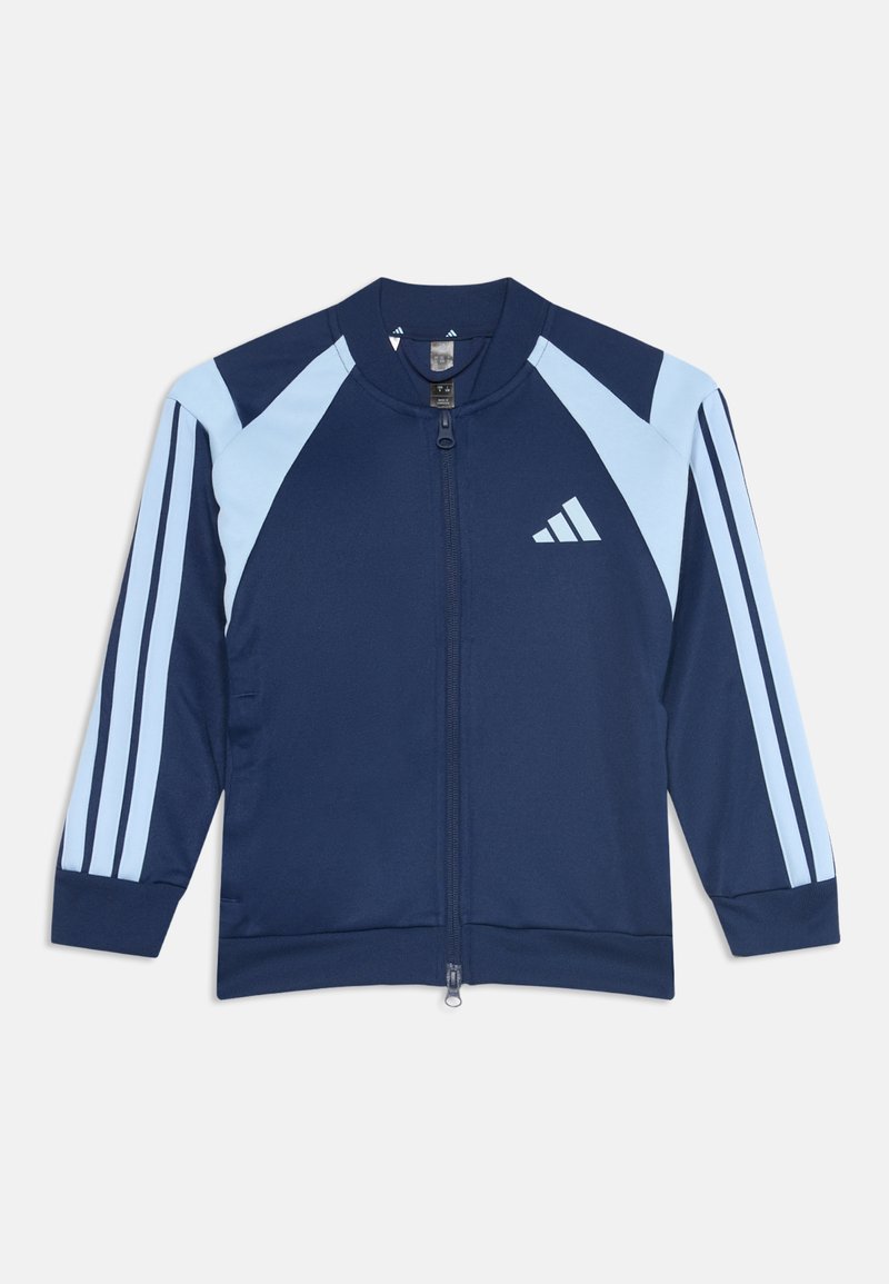Τζάκετ Adidas σε ναυτικό και ανοιχτό μπλε με φερμουάρ, με τρεις ρίγες στα μανίκια και λογότυπο στο στήθος, το οποίο είναι απλωμένο επίπεδα σε λευκό φόντο.