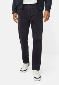 Donkerpaarse corduroy broek met een rechte snit, voorzien van steekzakken en een knoopsluiting, gecombineerd met witte sneakers met marineblauwe accenten.