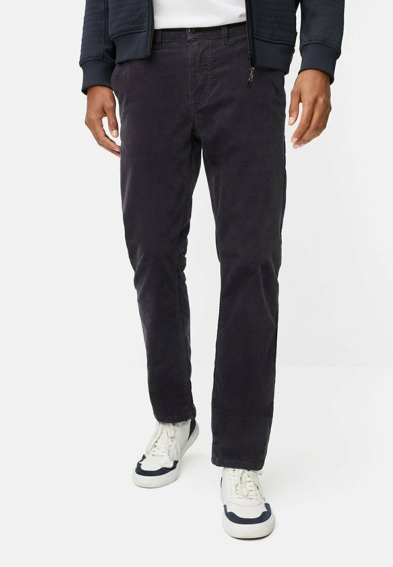Donkerpaarse corduroy broek met een rechte snit, voorzien van steekzakken en een knoopsluiting, gecombineerd met witte sneakers met marineblauwe accenten.
