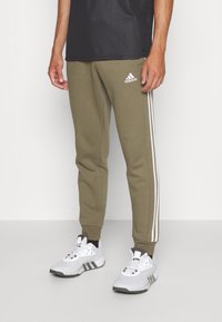 adidas Sportswear ESSENTIALS TAPERED CUFF 3-STRIPES  - Treniņtērpa apakšdaļas - olive strata