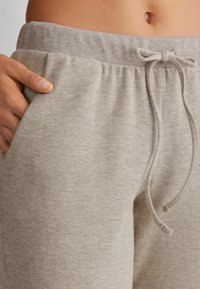Hellgraue Jogginghosen aus weichem Material, mit elastischem Bund, Kordelzug und Seitentaschen. Strukturierter Stoff.