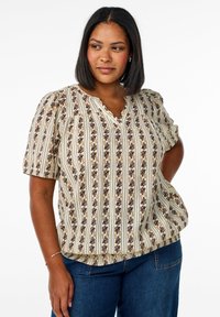 Short-sleeve blouse in cream with vertical blue and brown floral patterns. V-neck design and relaxed fit. Lightweight fabric with textured detail.