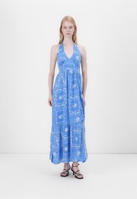 Blaues, ärmelloses Maxikleid mit Halterneck, das mit floralen Mustern und einem gestuften Rock ausgestattet ist. Glattes Material und entspannter Schnitt. Schwarze, geschnürte Sandalen.