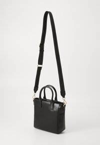 Sac fourre-tout en cuir synthétique noir avec deux poignées supérieures et une longue sangle ajustable. Équipé de quincaillerie dorée et d'une surface texturée.