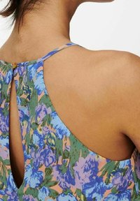 Mouwloze top met bloemenpatroon en een keyhole-ontwerp aan de achterkant, overwegend groen met blauwe en roze accenten, gemaakt van lichte stof.
