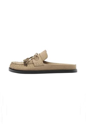 Mocassino beige in camoscio senza retro con fiocco nappine e punta mocassino cucita su suola piatta nera, mostrato di profilo.