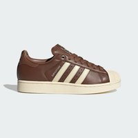 Καφέ δερμάτινο αθλητικό παπούτσι Adidas Superstar με κρεμ χρώμα στη μύτη, τρεις ρίγες και κείμενο "Superstar" σε ανοιχτό φόντο.