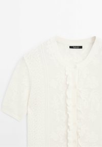 Cardigan court en maille blanc à motif floral, patte de boutonnage à volants et col rond signé Massimo Dutti.