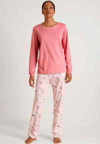 Roze langemouwen top met een ronde hals gecombineerd met roze pyjamabroek met een speels dierenpatroon in zwart en grijs.