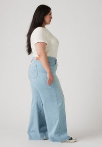 Light blue wide-leg jeans made of denim, featuring a high waist, a five-pocket design, and subtle stitching details on the back pockets.
