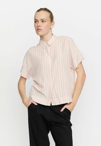 Light pink short-sleeve shirt with vertical stripes, button-down collar, and a relaxed fit, paired with black trousers.